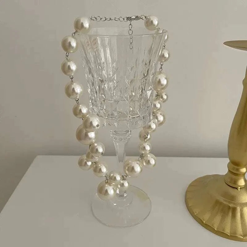 Elegant imitation pearl women's necklace with large round beads choker displayed on glass goblet, suitable for wedding and party wear
