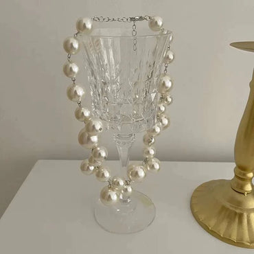 Elegant imitation pearl women's necklace with large round beads choker displayed on glass goblet, suitable for wedding and party wear