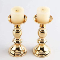 Pair of elegant golden candle holders with white pillar candles for wedding and home decor