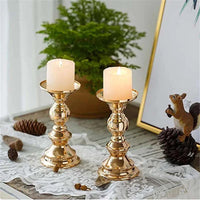 Pair of elegant golden candle holders with white candles on a lace-covered wooden table decor