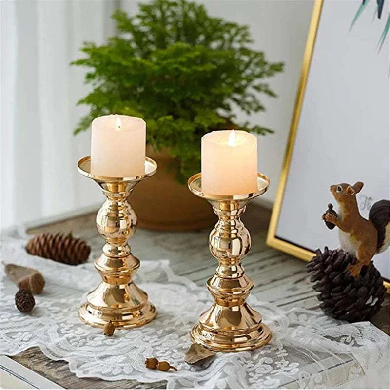 Pair of elegant golden candle holders with white candles on a lace-covered wooden table decor