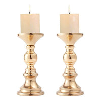 Pair of elegant golden candle holders with white candles for wedding and home decor