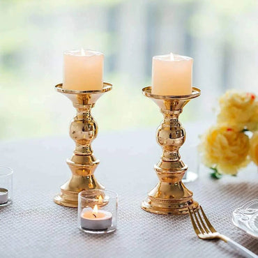 Pair of elegant golden candle holders with white candles on a table decorated for wedding or special occasion